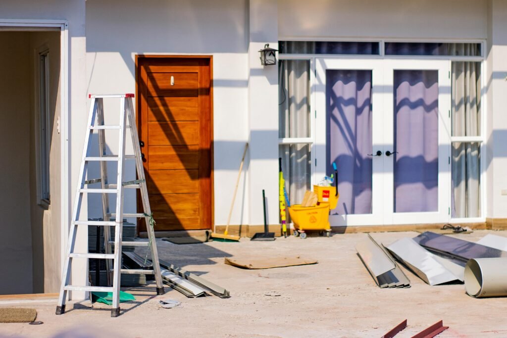 pexels-photo-4567374-4567374 Front entrance of a house under renovation with tools and materials scattered around.